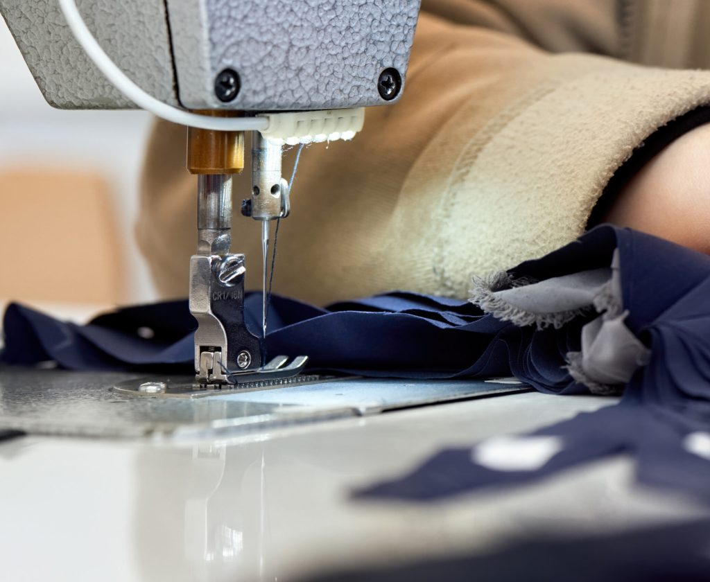 Woman working on a sewing machine. Blue cloth